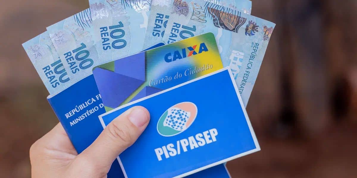 Pessoa segurando cartao do PISPasep carteira de trabalho cartao da caixa e dinheiro